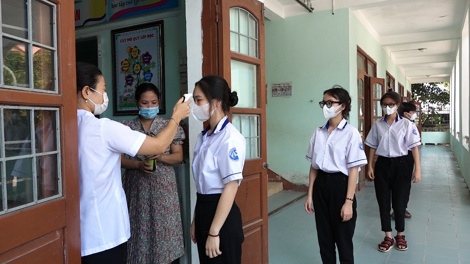 Các em học sinh được đo thân nhiệt và rửa tay sát khuẩn trước khi vào lớp